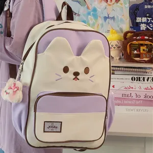 Detailed view of a cute pastel purple and cream cat-themed backpack with a plush charm.