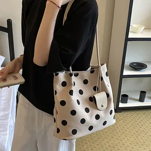 Detailed shot of a vintage cream polka dot tote bag carried in a casual lifestyle setting