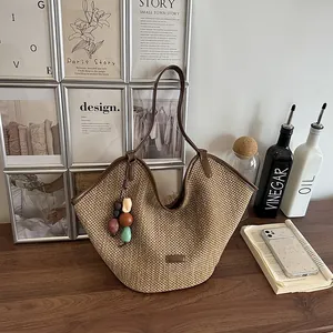Large handmade woven straw tote bag with dark leather trim and colorful bead charm