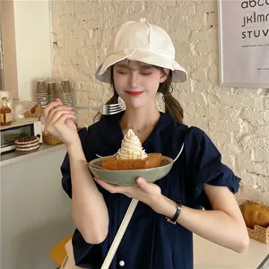 Girl wearing white ruffled bucket hat in a cozy cafe lifestyle setting.