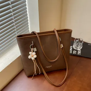 Close-up of brown textured tote bag with flower charm in a cozy room setting