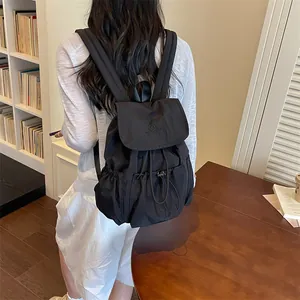 Stylish black drawstring pleated backpack for travel worn by a model in a library setting
