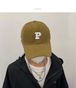 Close-up detail of mustard yellow baseball cap with white embroidered letter P on model