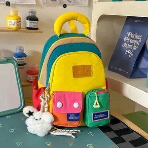 Vibrant multi-color patchwork student backpack featuring a cute fluffy bear charm detail.