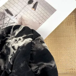 Macro view showing the detailed knit texture of the black and white tie-dye beanie