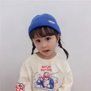 Close-up of a child wearing a blue knitted beanie with a PPSW patch on a soft background.