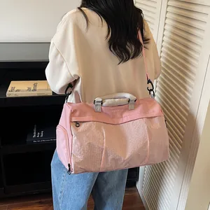 Model carrying a stylish pink travel duffel bag in a modern indoor lifestyle setting