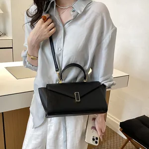 Close-up view of a stylish black leather handbag with a metal clasp worn by an Asian model.