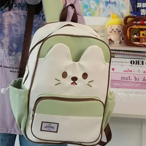 Detailed view of the cute cat face design on the green and white backpack