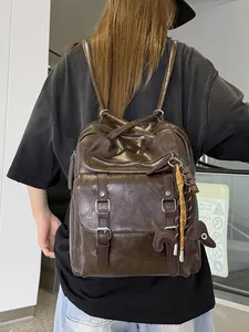 Vintage dark brown leather backpack with large capacity and cute dog charm for travel.