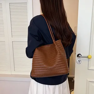 Woman wearing a retro brown woven tote bag over her shoulder in a stylish room.