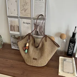 Close-up of a handmade straw woven tote bag with a colorful bead charm and brown straps