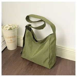 Detail view of a green checkered nylon shoulder bag with adjustable black strap buckle
