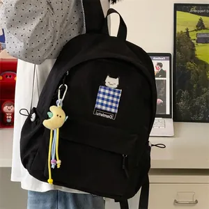 Detailed view of minimalist black student backpack with cute cat patch and moon charm