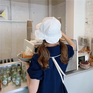 Detailed back view of a white lotus leaf edge bucket hat worn in a stylish cafe setting