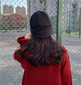 Back view detail showing the fit of a black warm Miki hat on long wavy brown hair.