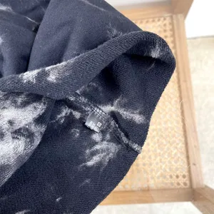 Detail view of a tie-dye slouchy beanie showing fabric texture and wash care label.