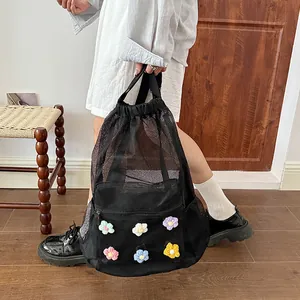 Detailed view of the black mesh drawstring backpack with colorful handmade crochet flowers.