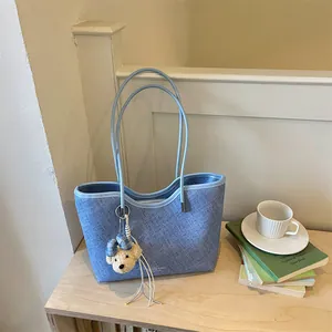 Macro view showing the fine denim texture and bear accessory of the stylish blue tote bag