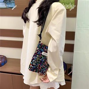 Dettaglio di una mini borsa a tracolla con paillettes colorate su una modella in bianco