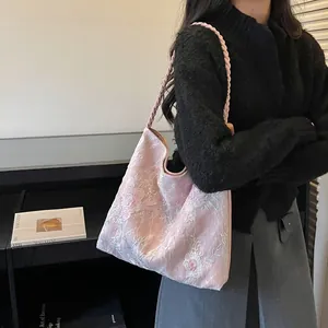 Lifestyle view of a pink floral embroidered hobo bag with a braided shoulder strap