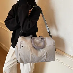 Minimalist grey travel duffel bag shown as worn by model in a lifestyle setting