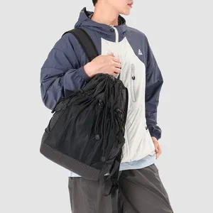Close-up view of a stylish women's black and grey grid drawstring backpack on model