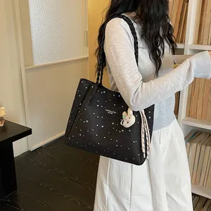 Grand sac cabas noir à motif d'étoiles blanches porté par un mannequin en détail