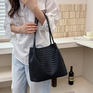 Elegant black vintage woven leather tote bag carried by model in casual setting