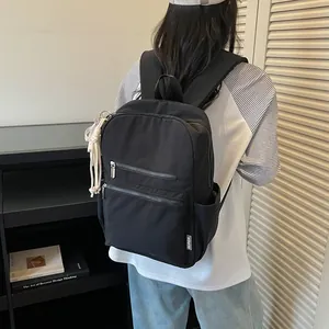 Mochila minimalista de nailon negro ligero mostrada desde una vista trasera en una modelo