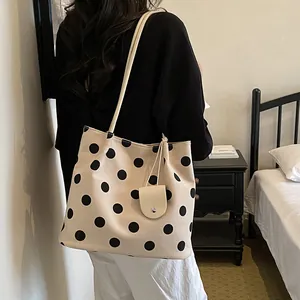 Stylish cream polka dot tote bag worn by a model in a cozy bedroom setting view