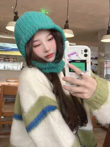 Detailed lifestyle view of a cozy green knitted balaclava hood on an Asian model in a cafe