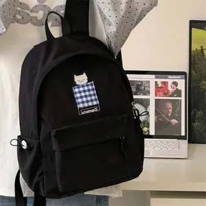 Close-up of black Japanese style backpack with cute cat patch and checkered detail
