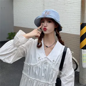 Close-up of a light blue bucket hat with cute rabbit ears embroidery on a female model.