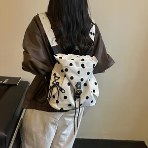 Stylish white canvas backpack with black polka dots shown on model for daily commuting