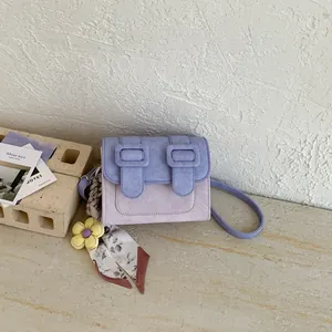 Detailed view of a trendy purple suede crossbody bag with a floral scarf accessory