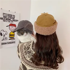 Back view of a woman wearing a mustard yellow Sherpa fleece earflap hat holding a cat