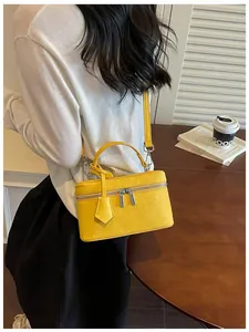 Detailed view of a yellow rectangular vanity box handbag with silver zipper hardware.