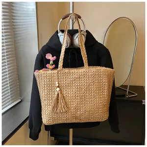 Gros plan d'un sac cabas en paille tissée minimaliste avec pampille et style