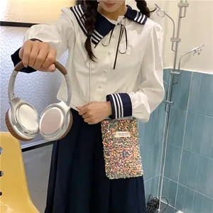 Dettaglio di una mini borsa a tracolla con paillettes colorate abbinata a un outfit studentesco