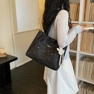 Vue de style de vie d'un sac cabas noir à imprimé étoiles avec un charmant porte-clés lapin