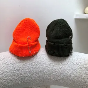 Detail of hip-hop knitted beanies with metal rings, safety pins and distressed edges.
