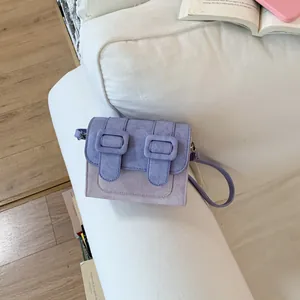 Top view of a stylish purple two-tone crossbody square bag on a white sofa