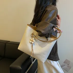 Elegant large capacity woven tote bag with flower charm shown on a model shoulder
