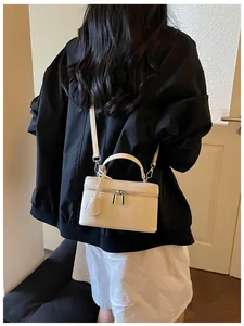 Back view of a model carrying a delicate cream white vanity box bag with strap
