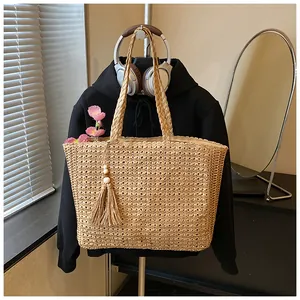 Sac cabas minimaliste en paille tressée avec pompon sur un sweat à capuche.