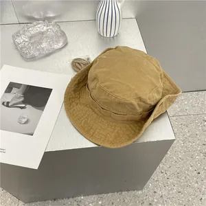 Close-up van een kaki katoenen vissershoed op een minimalistische grijze display