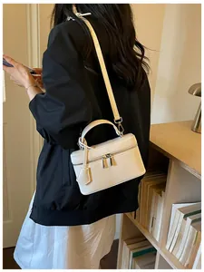 Small white vanity box bag worn as a crossbody bag in a lifestyle setting