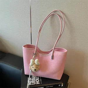 Detail view of a stylish pink minimalist tote bag featuring a cute teddy bear charm accessory