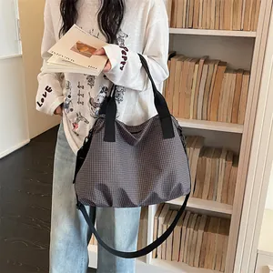 Primo piano di una grande borsa da viaggio a scacchi grigi portata da una modella